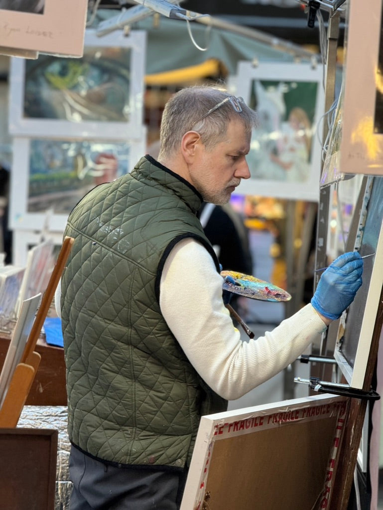 a man in a green vest is painting a picture